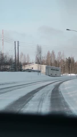 Winter road in Finland. View from the car from the passenger seat. Sunlight midday. Vertical shot.