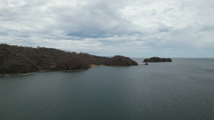 Pan over El Jobo bay in Costa Rica to Isla Chancleta and revealing Playa Jada over the Pacific Ocean waters