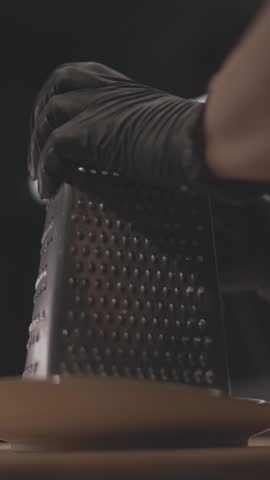 A vertical close-up shot of a grater in use.