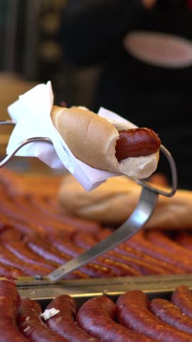 Hot dog small street market details. Hands of seller and customer. sausages and bread Vertical shot.