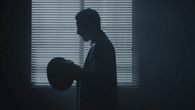 Noir spy film character puts hat on in a dark room next to the window backlight. High quality 4k footage - Powered by Shutterstock - Get 15% off with code: PIKWIZARD15