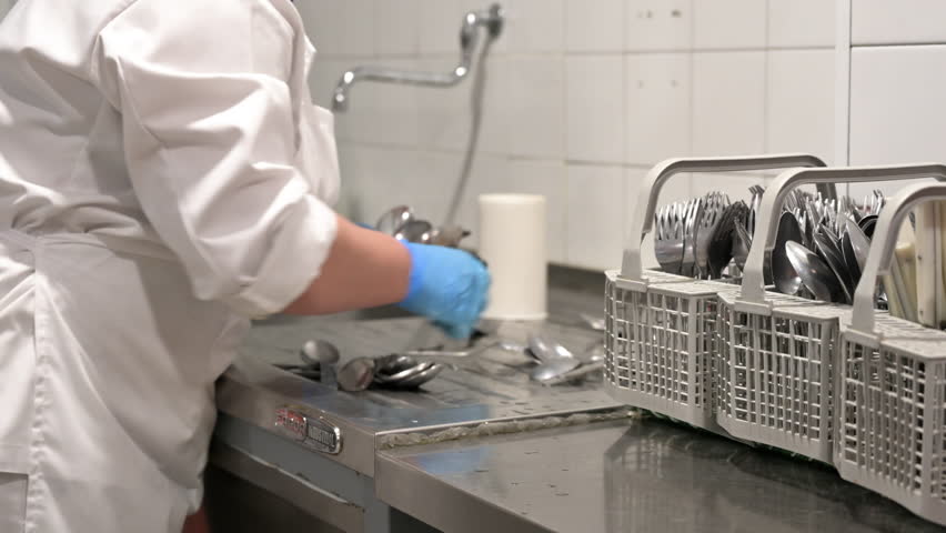 Unrecognizable woman, preparing dirty cutlery for washing at the dishwasher in commercial kitchen. High quality 4k footage