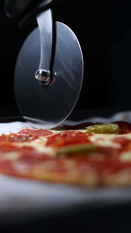 A vertical slow-motion shot of pizza being sliced.
