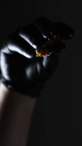 A shot of someone with balck gloves dropping small bread cuts on the camera.