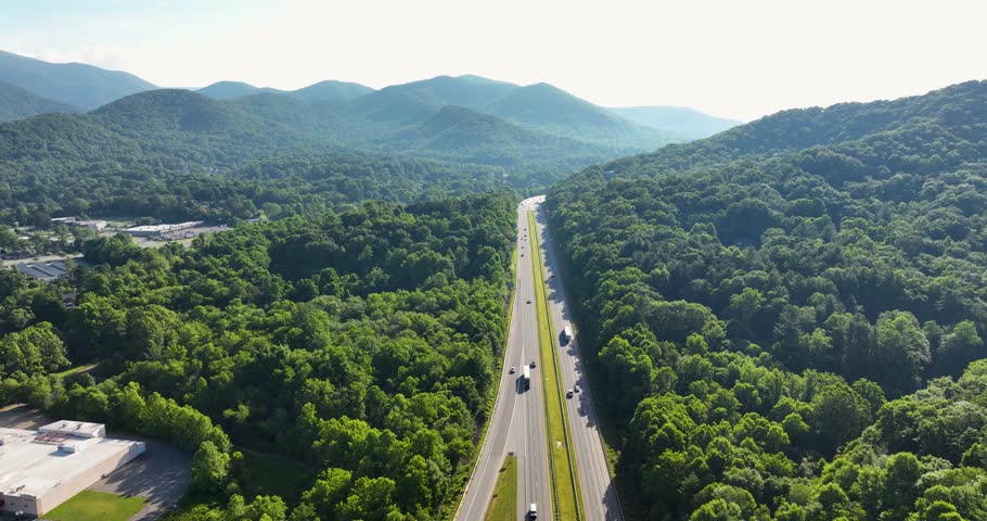 Aerial view of Interstate 40 cutting through lush green forests in Black Mountain, NC, with scenic mountains in the background.