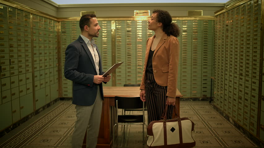 A businessman and a businesswoman inside the vault room engaging in a serious conversation