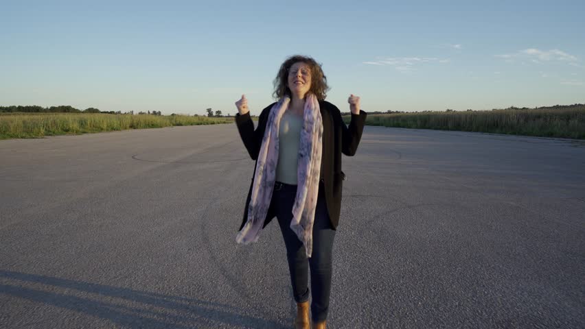 Very happy woman jumping, dancing, clapping and spinning on a landing strip.