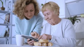 Adult daughter teaches elderly mother how to use tablet with internet access modern life ensuring comfort ease for aging parents. Blending of technology familial care comfortable connected old age. - Powered by Shutterstock - Get 15% off with code: PIKWIZARD15