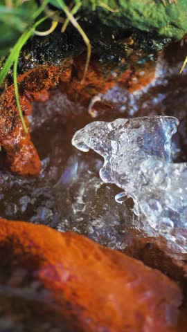 Vertical video: pulsating clear water in a mountain spring among stones in slow motion. Drinking spring of mineral water. Reserves of fresh, clean water on the planet