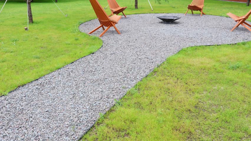 Summer relax zone outdoors near the house with wooden chairs and fireplace. Patio at home yard. Gazebo.