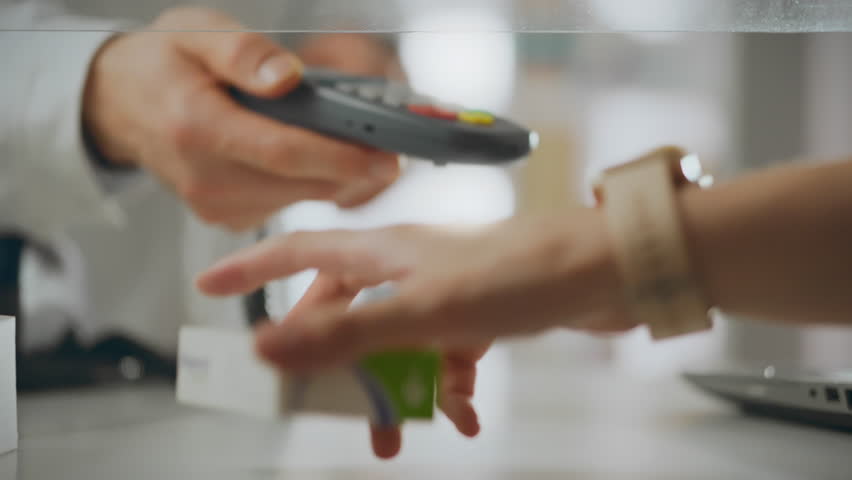 Using a smartwatch, a young modern girl pays for pills at the pharmacy. Online payment process using modern gadgets. She places the smartwatch on the payment terminal