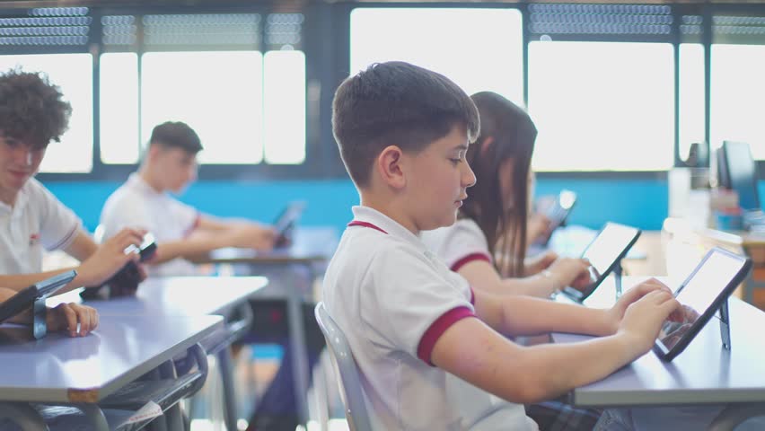Young students engaged in learning activities on tablets in a classroom setting. - Powered by Shutterstock - Get 15% off with code: PIKWIZARD15