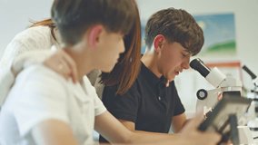 Schoolboys in a science lab, focused on an experiment with a microscope and tablet. - Powered by Shutterstock - Get 15% off with code: PIKWIZARD15
