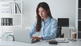 Focused businesswoman working on laptop at modern office desk, surrounded by files, coffee cup, and organized workspace, indicating productivity - Powered by Shutterstock - Get 15% off with code: PIKWIZARD15