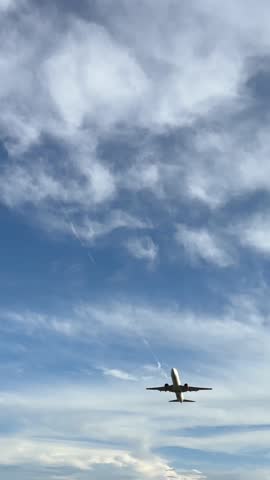 4k vertical footage of an airplane taking off, bright blue and white sky background