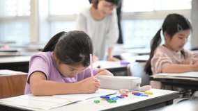 A Japanese primary school girl studying with a pencil during an English lesson in a classroom. Video of her looking up and copying the blackboard into her notebook. - Powered by Shutterstock - Get 15% off with code: PIKWIZARD15