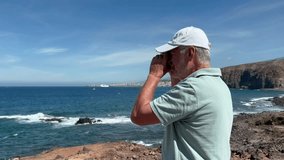 Happy smiling senior man in vacation at sea admiring the seascape and the ocean waves. Elderly male with hat takes photos for memory, horizon over water - Powered by Shutterstock - Get 15% off with code: PIKWIZARD15
