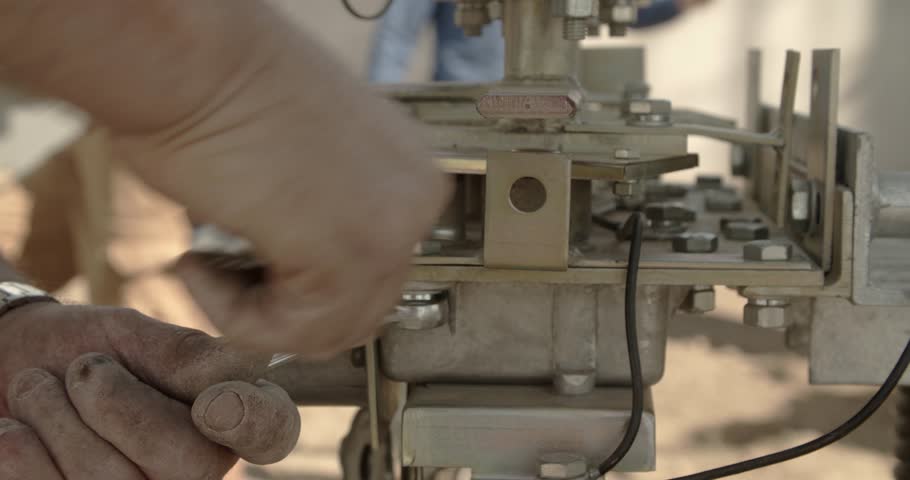 Repair of parts. The worker tightens the bolts in the metal part of the mechanism.