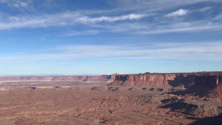 Slow panning shot of the iconic Canyonlands National Park from Grand View Point with beautiful blue sky and clouds. The vast landscape stretches out showcasing the beauty of nature - Utah, USA