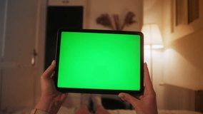 Girl with green screen display. Hands hold horizontal tablet close up. Person watching video or movie using digital tablet.