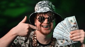 Rich man bragging about wealth showing his money and gold to camera, portrait of millionaire. Funny male person mad about dollars smiling with his golden teeth, swaying dollars banknotes in hand - Powered by Shutterstock - Get 15% off with code: PIKWIZARD15