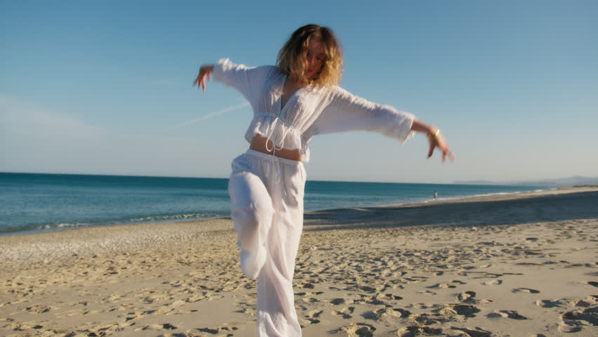 Girl Dressed In White Dances On The Beach Near The Ocean
