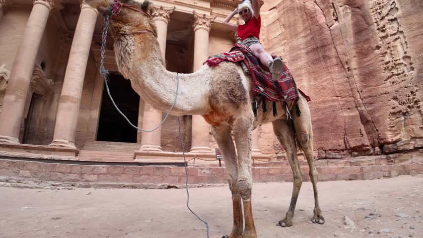 Tourist is enjoying a camel ride in front of Al Khazneh, the Treasury at Petra, a unesco world heritage site in Jordan
