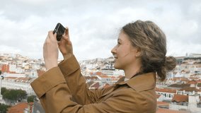Woman Taking Photo with Smartphone Overlooking Lisbon Cityscape - Urban Exploration and Photography. Girl in raincoat walks through historic center of Lisbon and takes pictures of views and - Powered by Shutterstock - Get 15% off with code: PIKWIZARD15