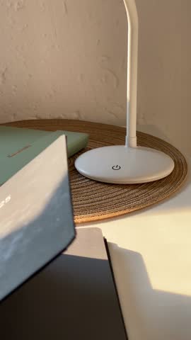 A notebook is leafing through on the table, the lamp can be seen in another notebook.