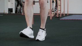 Low section of male legs skipping with jump rope. Male athlete wearing white shoes exercising at gym. He is doing crossfit training in GYM. - Powered by Shutterstock - Get 15% off with code: PIKWIZARD15