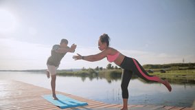 Close view of African American couple practicing yoga next to large pond. Teaching each other correct techniques. Man following different types of exercise after his personal trainer. - Powered by Shutterstock - Get 15% off with code: PIKWIZARD15