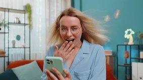 Oh my God Wow. Excited happy joyful winner young woman freelancer using smartphone looking at screen browsing celebrating win good message news. Businesswoman with windswept hair tapping on the phone. - Powered by Shutterstock - Get 15% off with code: PIKWIZARD15