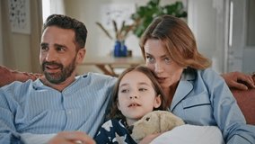 Funny family watching movie having fun at light interior closeup. Positive child girl eating popcorn holding teddy bear at apartment. Carefree father mother and daughter relaxing together at weekend - Powered by Shutterstock - Get 15% off with code: PIKWIZARD15