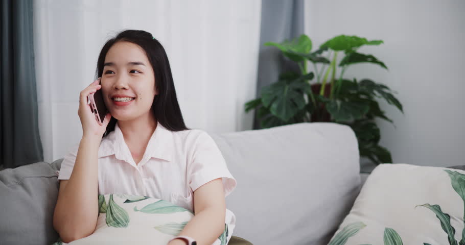 Footage dolly shot ,Carefree young woman talking with her friend on cell phone on sofa at home ,Lifestyle with device technology, talking and smile with happy