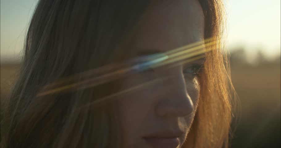 Closeup of woman enjoying the calm, peaceful and serene summer sunset with light shining on her hair during golden hour in cinematic slow motion.