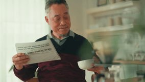 Asian male man gray hair senior retired enjoying coffee breakfast at kitchen counter weekend while reading newspaper Smiling senior man with book while sitting in kitchen at home healthy lifestyle - Powered by Shutterstock - Get 15% off with code: PIKWIZARD15