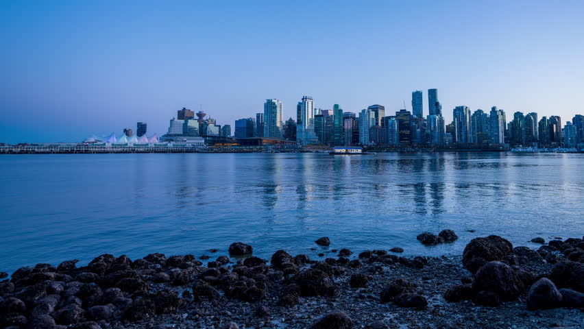 Vancouver downtown city skyline. Colorful buildings lights reflected in water. Time-lapse sunset to night. British Columbia, Canada.