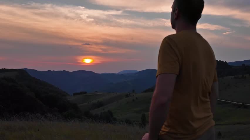 Silhouette of a man looking at the mountain sunset.	
