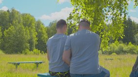 Father talking to his teenage son while sitting on a bench on a summer day. View from the back. - Powered by Shutterstock - Get 15% off with code: PIKWIZARD15