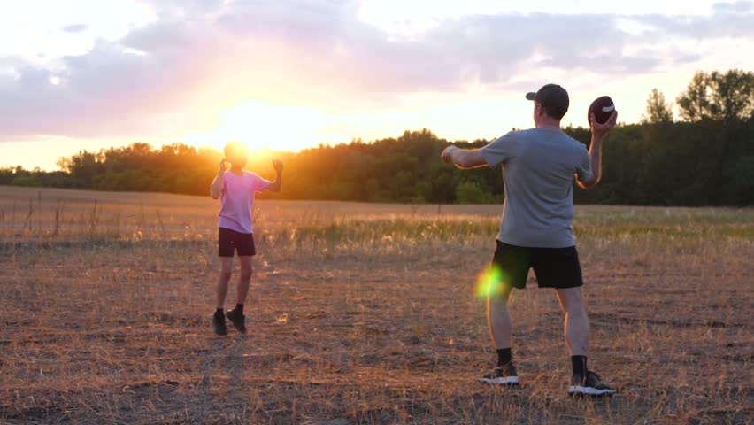 fun family games kid and dad play ball. family play in american football summer. happy family playing together. dad and son
