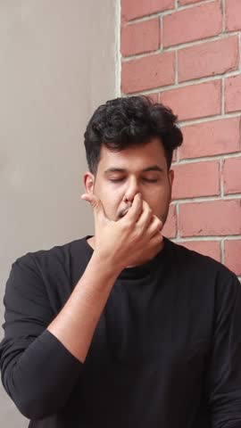 Indian man is practicing yoga and breathing excercise. he is doing nadi shodhana pranayam. alternate nostril breathing helps to increase the lungs capacity. it calms the body and increase focus .
