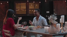 Two friends enjoying a dinner together at a countryside house in the woods, surrounded by candlelight. Friends Dining at a Countryside House in the Evening - Powered by Shutterstock - Get 15% off with code: PIKWIZARD15