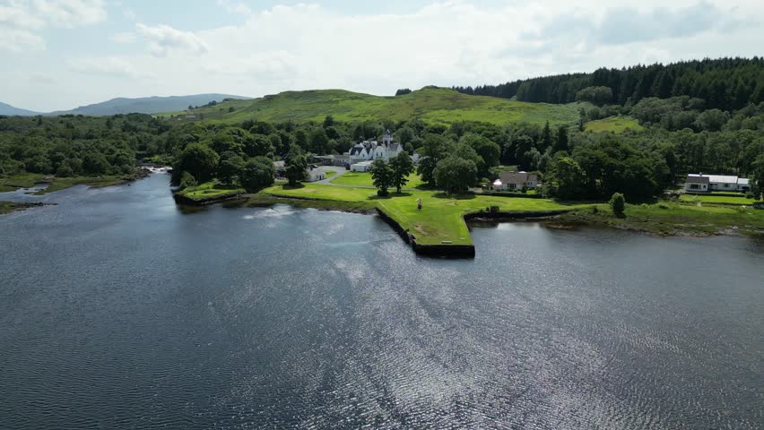 hotel scotland aerial drone shot distance isle of skye windy day lake green grass trees water helicopter parked front