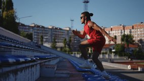 Slow motion. Stylish male athlete quickly runs up, jumping over steps, on the stairs of the stadium. Man in sunglasses and dreadlocks training outdoors on a warm autumn day - Powered by Shutterstock - Get 15% off with code: PIKWIZARD15