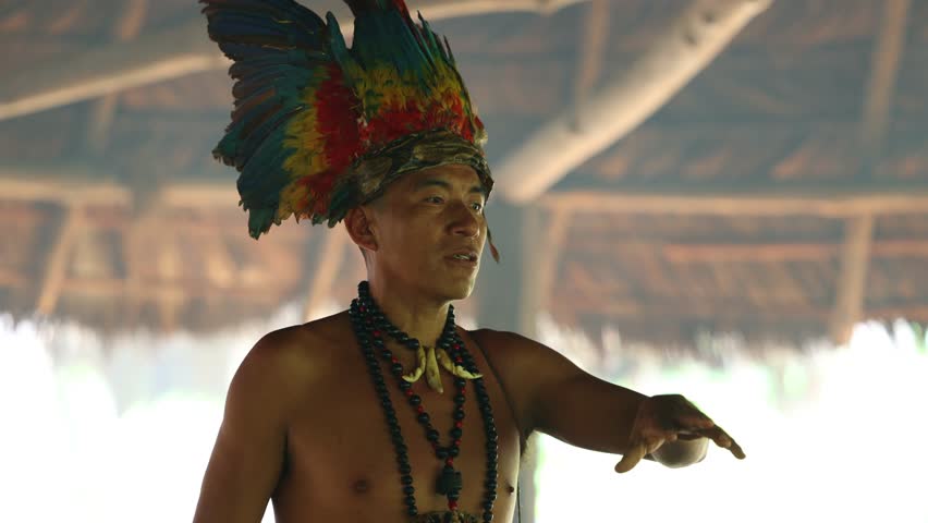 close-up of a Wayuri tribe member adorned with a feather crown, participating in a traditional ceremony in the Ecuadorian Amazon rainforest.