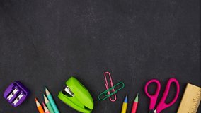 Colorful school supplies moving bottom border. Top down view over a black chalkboard background. Back to school concept. - Powered by Shutterstock - Get 15% off with code: PIKWIZARD15