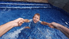 Father holds hands of son and spin him around, standing in shallow pool. First person view perspective captures toddler shining face and splashes on water from his feet. Young child laughs and giggles - Powered by Shutterstock - Get 15% off with code: PIKWIZARD15