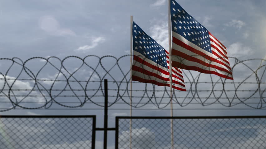 USA waving flag on country border concept. American blowing banner with barbed wire fence.