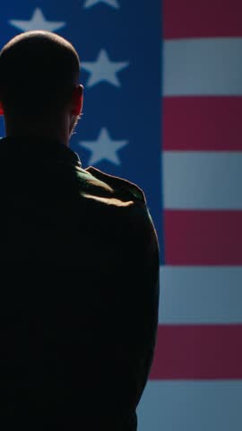 Vertical video Soldier saluting USA flag, participating in 4th of July celebrations. United States of America veteran honoring country during memorial day event, doing patriotic hand gesture towards