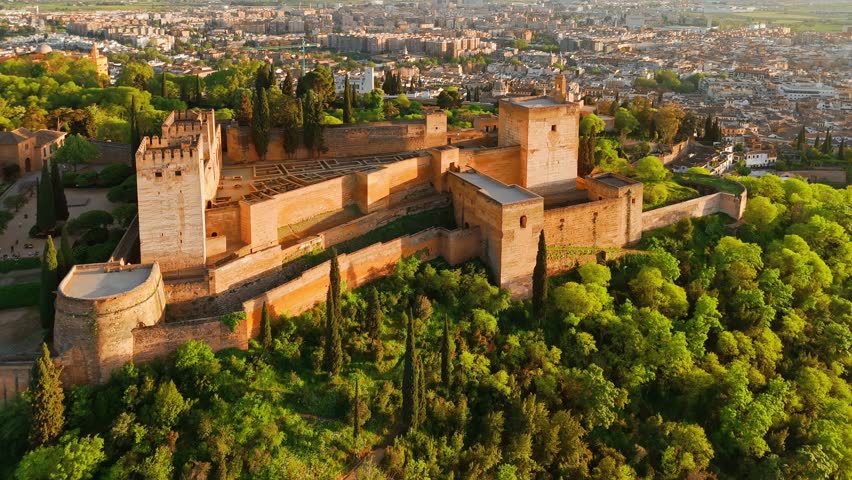 Aerial view of the historic Alhambra palace at sunset in Granada, Andalusia, Spain. The ancient Arabic fortress Alhambra during the beautiful evening. Aerial drone footage of Granada cityscape